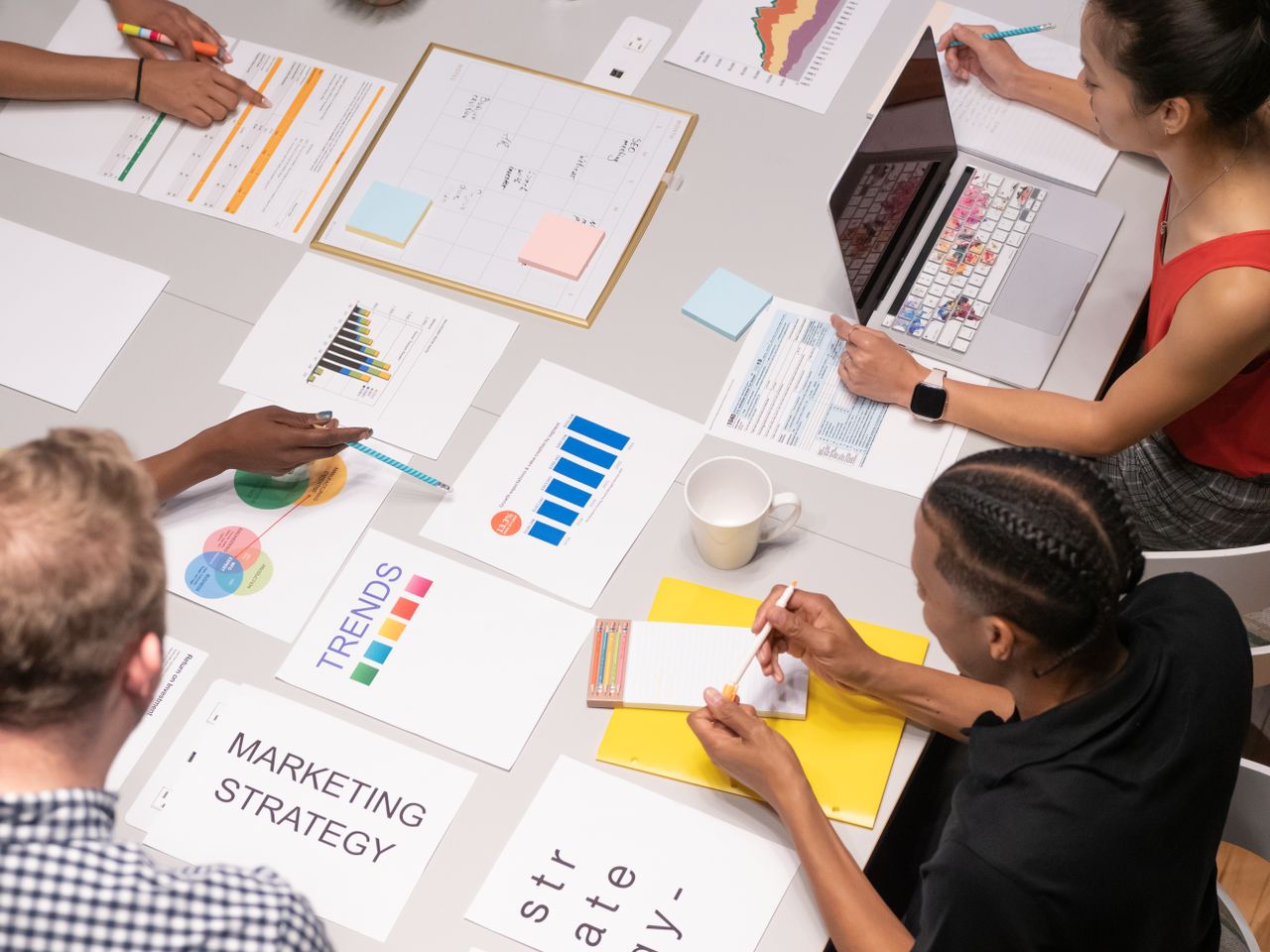 Overhead view of a diverse team reviewing marketing strategies through charts and graphs.
